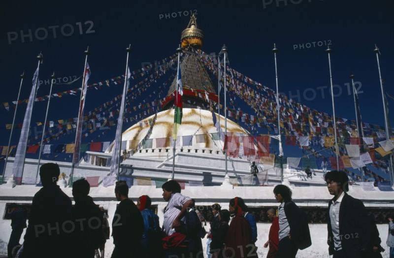 NEPAL, Bodhanath, "Pilgrims circling clockwise around Bodhanath Stupa draped with prayer flags during Loshar, the Tibetan New Year"