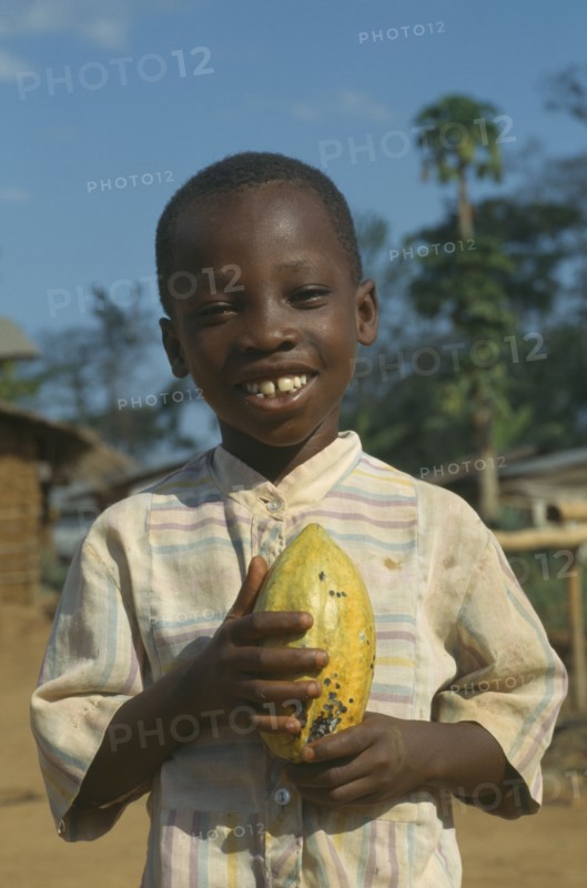 GHANA, West, Children, Portrait of child holding cocoa pod.