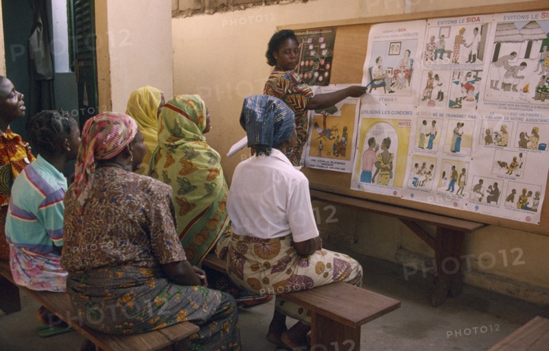 TOGO, Lome, Female teacher using story boards to demonstrate AIDS awareness and safe sex messages to group of women.