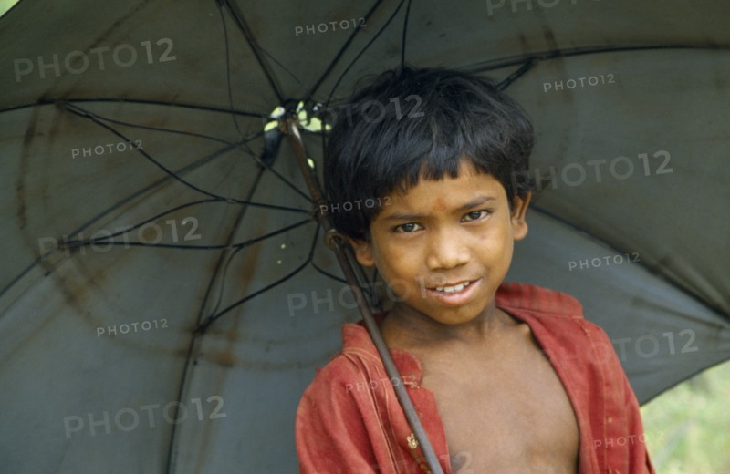 NEPAL, Terai Region, Children, Portrait of schoolboy with an umbrella.