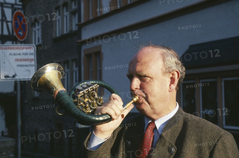 GERMANY, Rheinland Pfalz, Bernkastel, Man blowing hunting horn in town in the Mosel Valley.