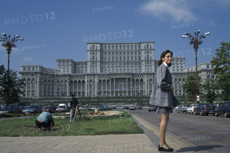 ROMANIA, Bucharest, House of the Republic.  Palace of former Communist president Nicholae Ceausescu.  Exterior facade with young woman standing in foreground.