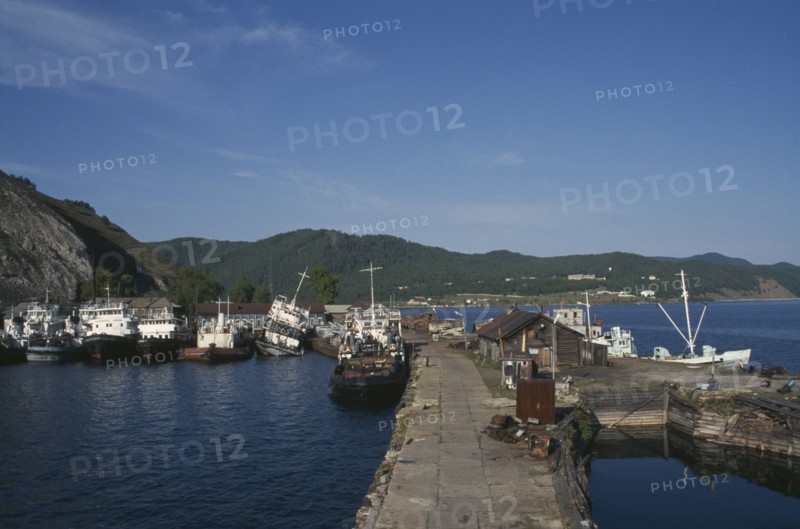 RUSSIA, Siberia, Lake Baikal, Fishing boats moored against stone jetty in lake harbour.