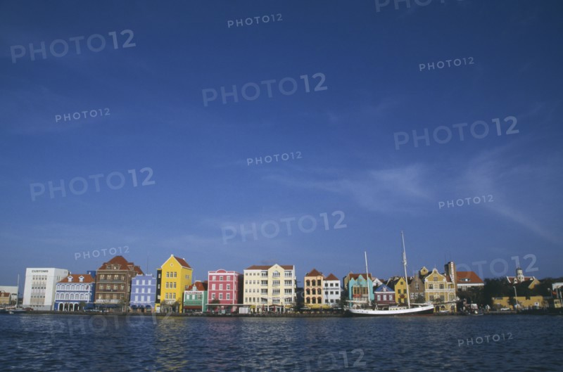 WEST INDIES, Dutch Antilles, Curacao, Willemstad.  Colourful waterfront buildings and moored sailing ship.
