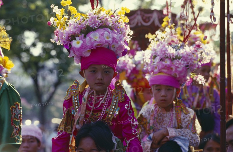 THAILAND, North, Chiang Mai, Two Luk Kaew or Crystal Children in costume carried on shoulders of adults to Shan ordination ritual at Wat Pa Pao.