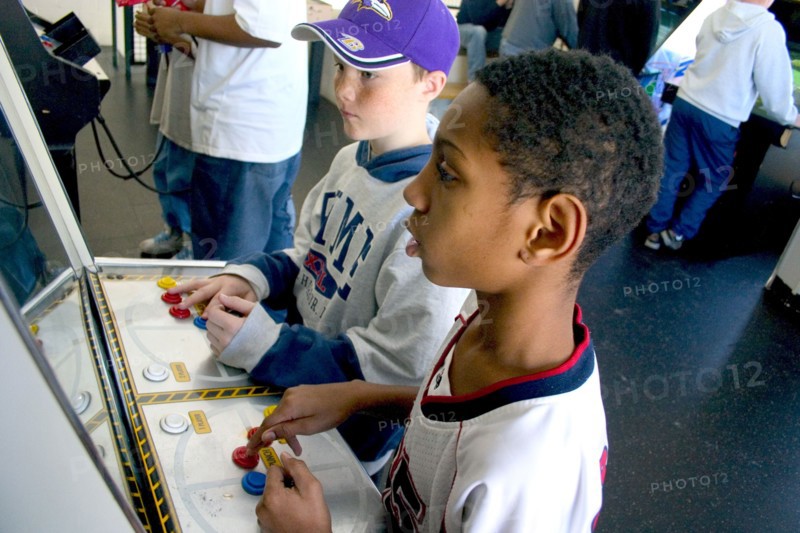 USA, Minnesota, St Paul, Friends age 10 playing video games developing their eye hand coordination at the Youth Express activity center.