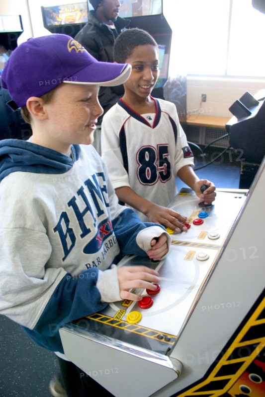 USA, Minnesota, St Paul, Friends age 10 playing video games developing their eye hand coordination at the Youth Express inner city activity center