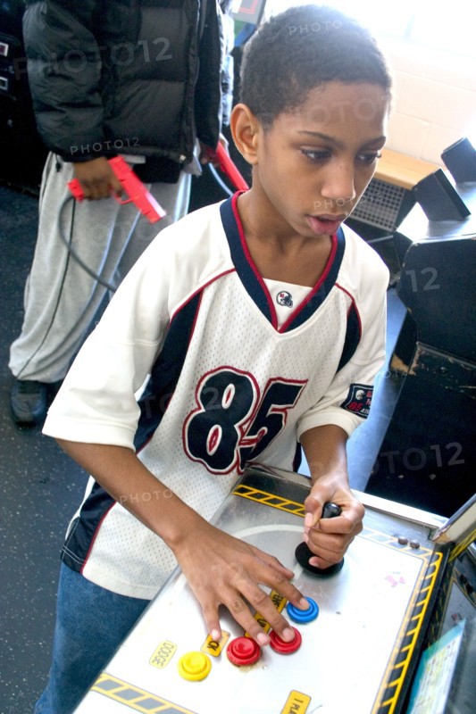 USA, Minnesota, St Paul, Young black child aged 10 playing video games developing his eye hand coordination at the Youth Express inner city activity center.