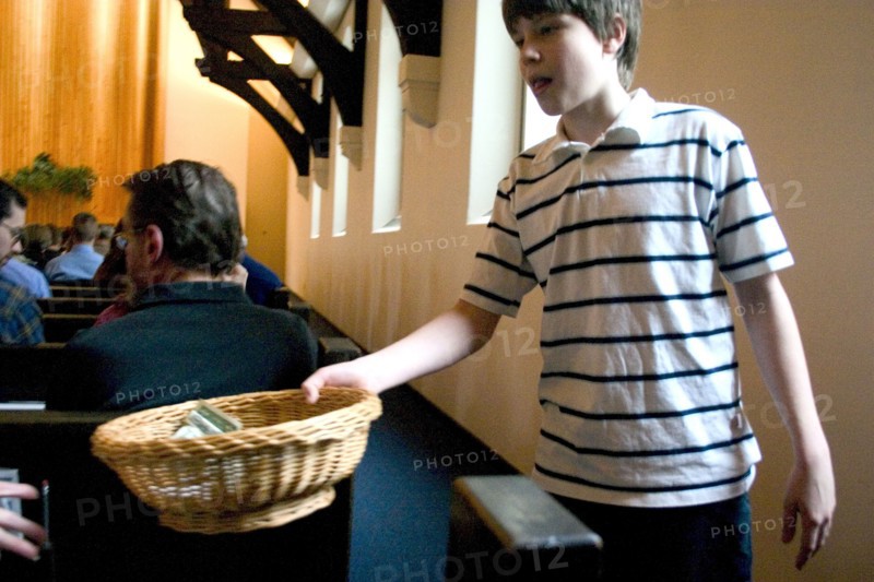 USA, Minnesota, St Paul, Young boy passing the offering basket at Unity Church Unitarian.