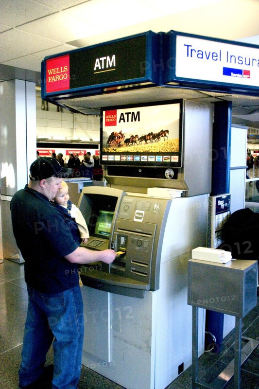 USA, Minnesota, Minneapolis, Father with baby son withdrawing cash at the ATM machine in the Minneapolis-St. Paul International Airport Charles Lindbergh Terminal.