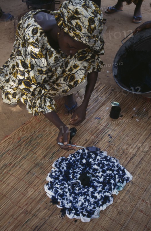 GAMBIA, Work, Woman using indigo coloured dye to tie dye fabric.
