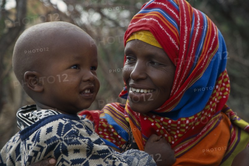 SOMALIA, Near Hargeisa, Portrait of mother wearing colourful headscarf holding and looking at her child