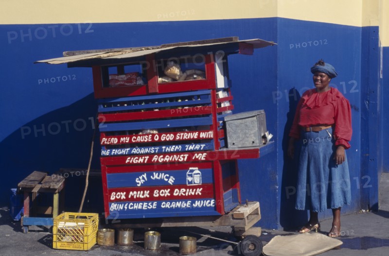 WEST INDIES, Jamaica, Kingston, Street vendor with religious text painted on stall.