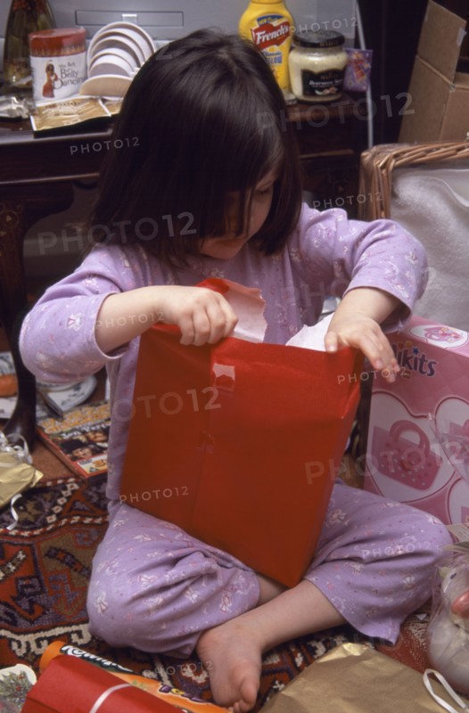 FESTIVALS, Christmas, Presents, Five year old girl sitting on the floor opening her Christmas presents