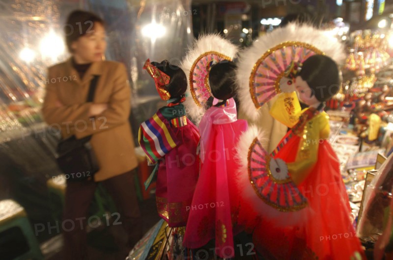KOREA, Seoul, "Namdaemun Market on a cold December night with customer looking at sounvenir dolls dressed in traditional Korean ""hanbok"""