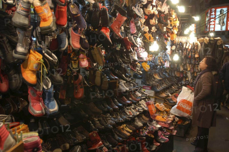 KOREA, Seoul, Namdaemun Market. Woman shopping for shoes on a cold December night