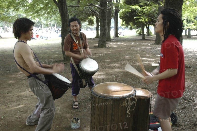 JAPAN, Honshu, Tokyo, "Harajuku. Yoyogi Park. Hiroaki Komura  and his brother Kenichi, with their friend Tomokazu Nagashima, playing African drums on a Saturday afternoon"