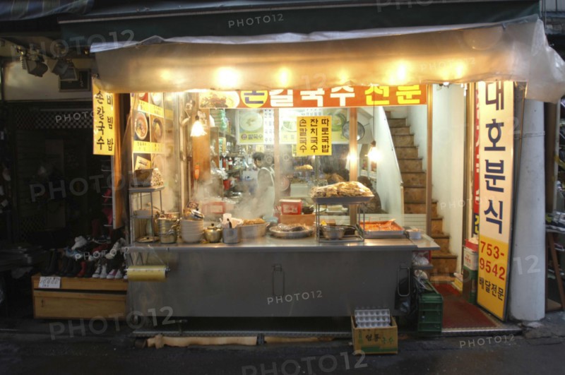KOREA, Seoul, Namdaemun Market at night in December. Streetside open restaurant with staff and customers