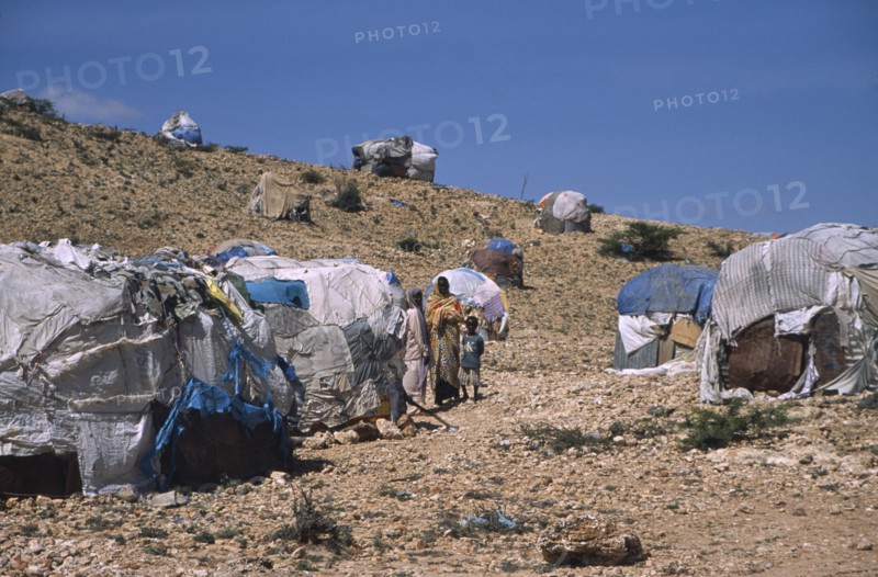 SOMALILAND, Hargeisa, The Kandahr IDP camp for Internally Displaced Persons.  Women and child standing between huts on barren hillside.