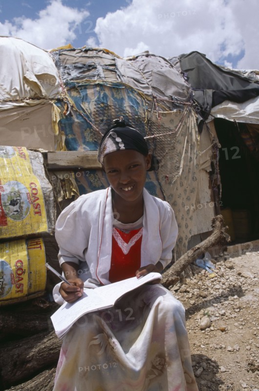 SOMALILAND, Hargeisa, Girl doing homework outside hut in Kandahar IDP camp.