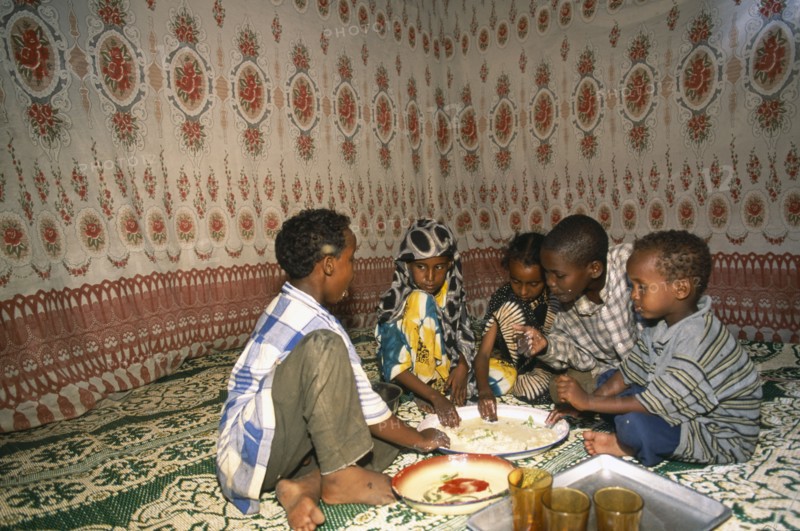 SOMALIA, Baidoa, Children eating meal at home from communal dish using the right hand.  At a family meal men are usually served first and women and children eat seperately later.