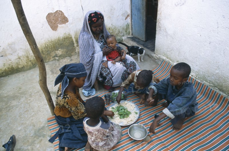 SOMALIA, Baidoa, Woman and children eating lunch from communal dish using the right hand.  At a family meal men are usually served first and women and children eat seperately later.