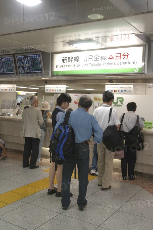 JAPAN, Tokyo , Tokyo station with customers waiting to buy Shinkansen aka bullet train tickets at a desk with bilingual signs above