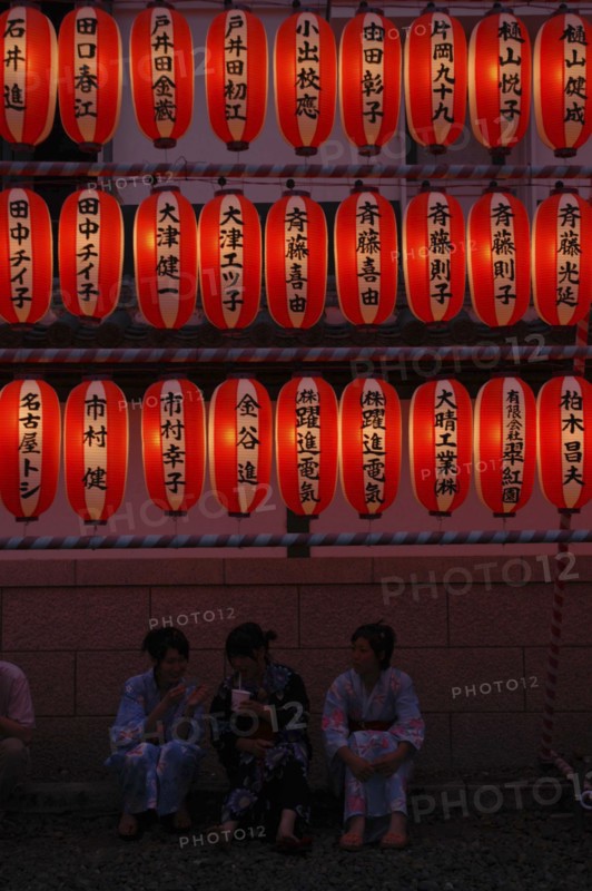 JAPAN, Chiba, Narita, "Teenage girls in yukata, summer kimono, sit beneath chochin lanterns each with the name of a donor to Narita san Temple during Gion Matsuri"