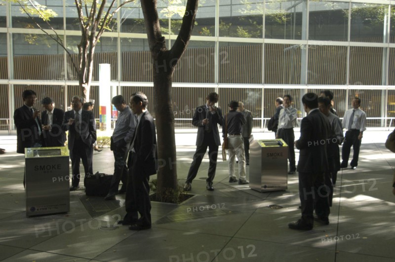 JAPAN, Honshu, Tokyo, "Yurakucho. A group of male salaried workers called salariman, smoking at a smoking station, during lunch hour at Tokyo International Forum  "