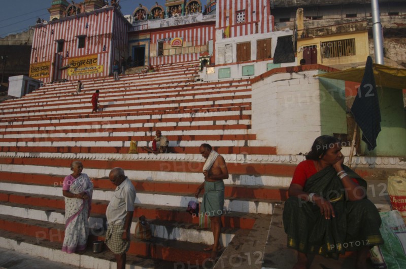 INDIA, Uttar Pradesh, Varanasi , Hindu worshippers on the steps of Kedar Ghat next to the Ganges River with steps leading up to Kedara Mandir temple in the early morning