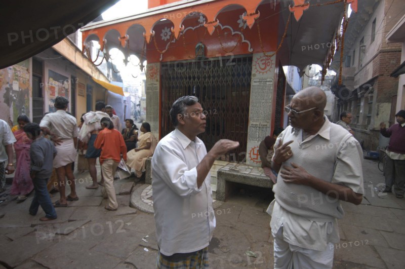 INDIA, Uttar Pradesh, Varanasi , Bengali Tole. Two middle aged men have a morning coversation outside a temple using their hands to stress the points they are making