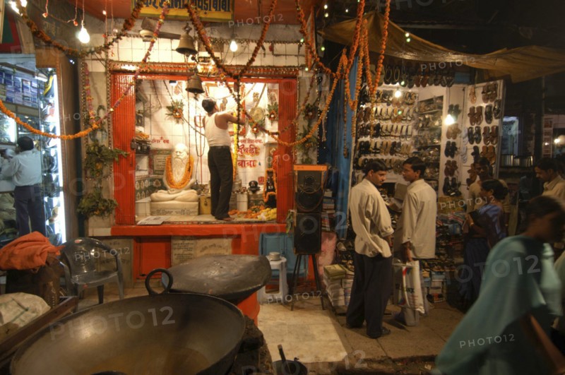 INDIA, Uttar Pradesh, Varanasi, Dasaswamedh Ghat. A man cleans the shrine of a Hindu saint in the market