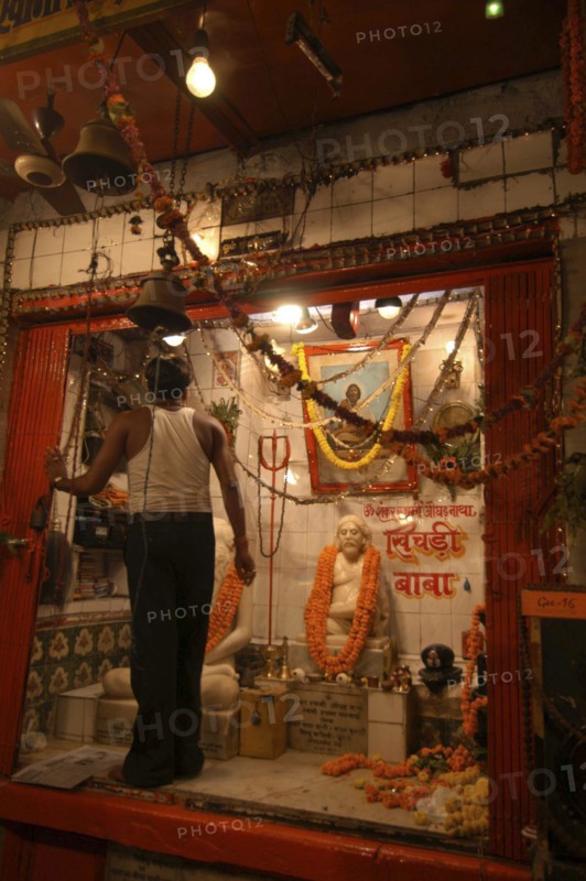 INDIA, Uttar Pradesh, Varanasi, Dasaswamedh Ghat with a man cleaning a shrine to a Hindu Saint