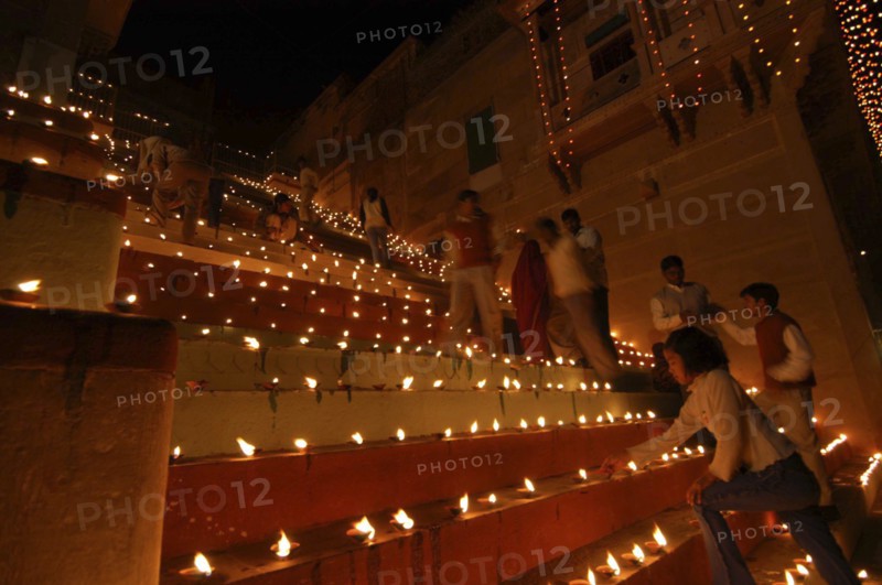 INDIA, Uttar Pradesh, Varanasi, Deep Diwali Festival. People lighting oil lamps on the steps leading down to the River Ganges