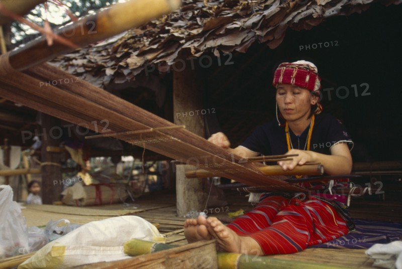 THAILAND, Chiang Mai, Sgaw Karen woman weaving cloth on a back strap loom