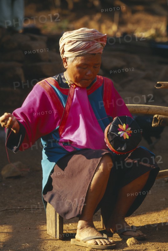 THAILAND, Chiang Rai Province, Doi Lan, Elderly Lisu woman embroidering a hat for a young boy at her residence