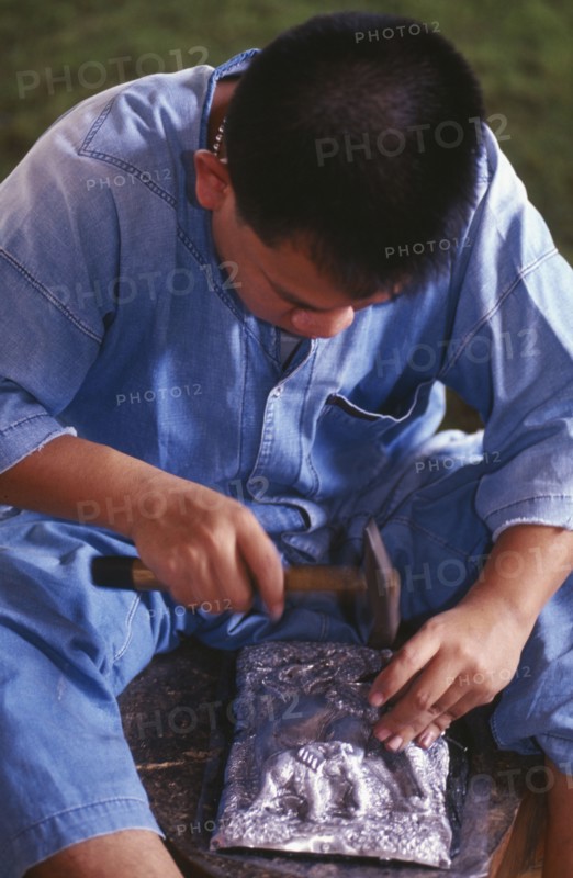THAILAND, Chiang Mai, Wat Sri Suphan, Silversmith making repousse picture of elephants
