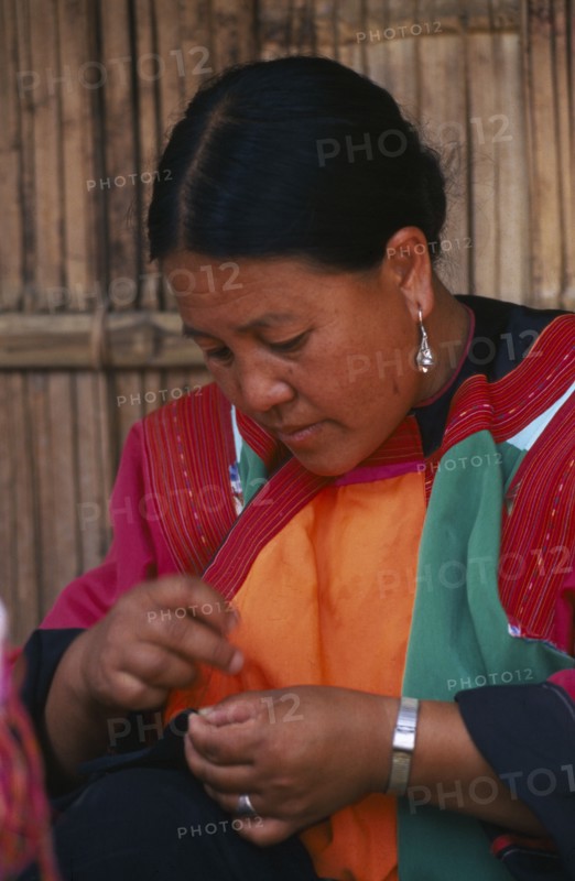 THAILAND, Chiang Mai Province, Lisu woman sewing in front of the house