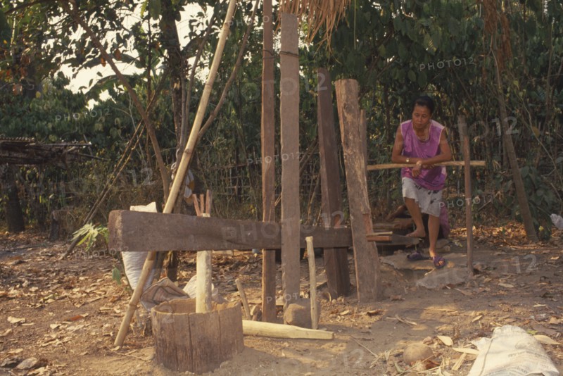 THAILAND, Chiang Mai Province, Mueng Keurt, Woman grinding coffee seeds with a foot powered mill to remove chaff