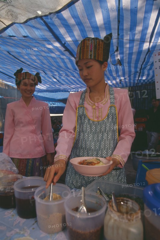 THAILAND, Chiang Mai, Wat Pa Pao, Two Shan women in traditional Shan attire at a food shop during Poi Sang Long
