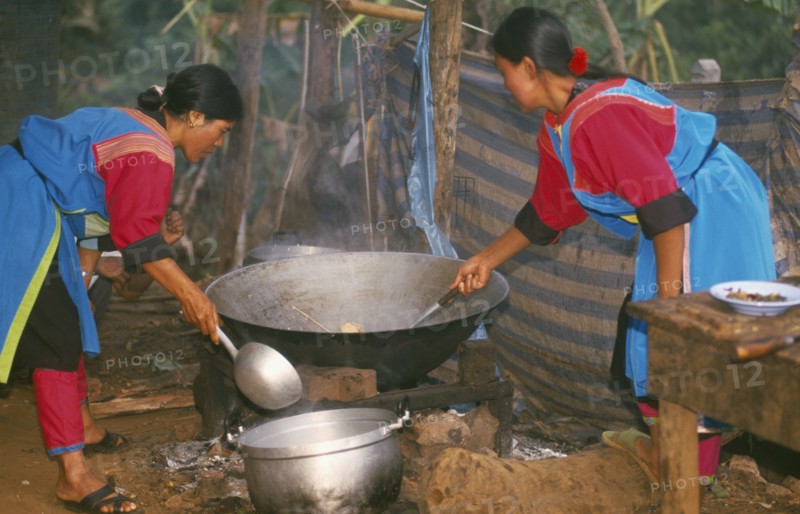 THAILAND, Chiang Rai Province, Huai Khrai, Lisu women stir frying a meal in a large wok for New Year dinner