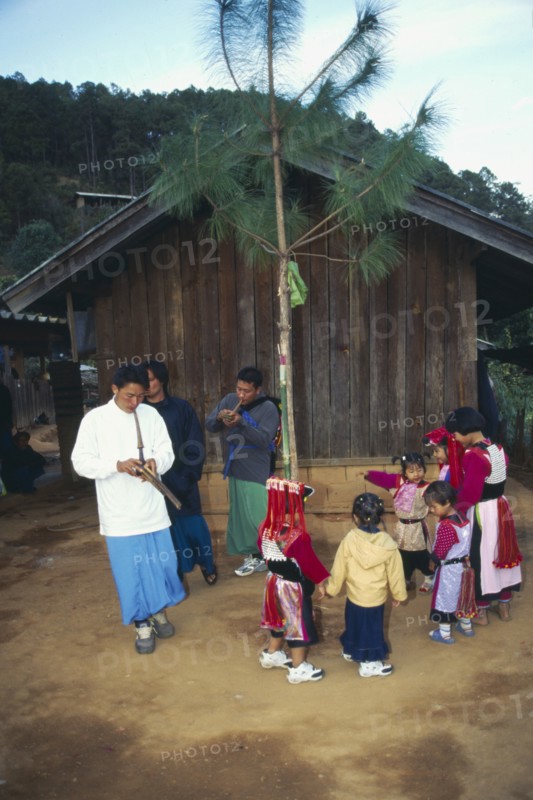 THAILAND, Chiang Rai Province, Doi Lan, Lisu men play gourd pipes as children dance around the New Year tree