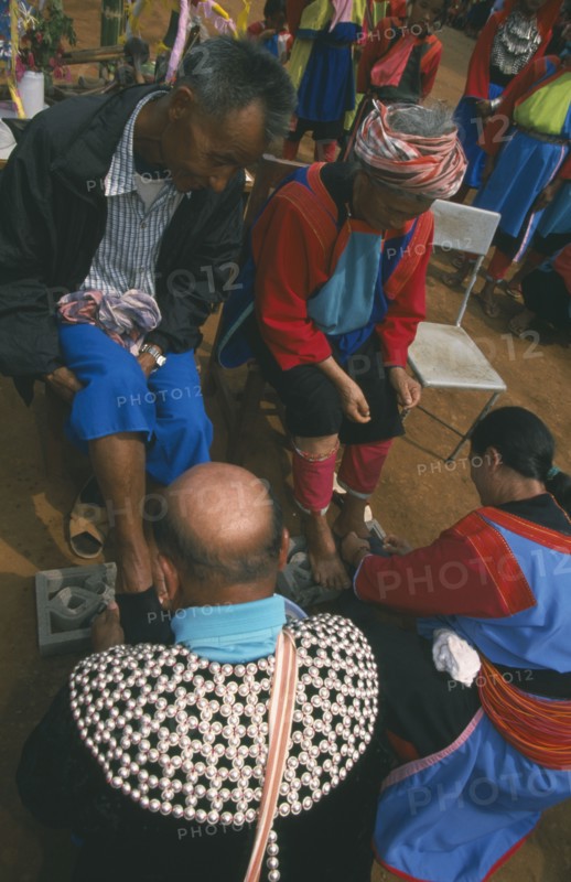 THAILAND, Chiang Rai Province, Huai Khrai, New Year. Lisu people paying respects to their elders by putting new socks on their feet