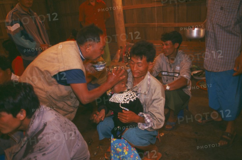 THAILAND, Chiang Rai Province, Doi Lan, Lisu shaman anointing supplicants head at healing ceremony