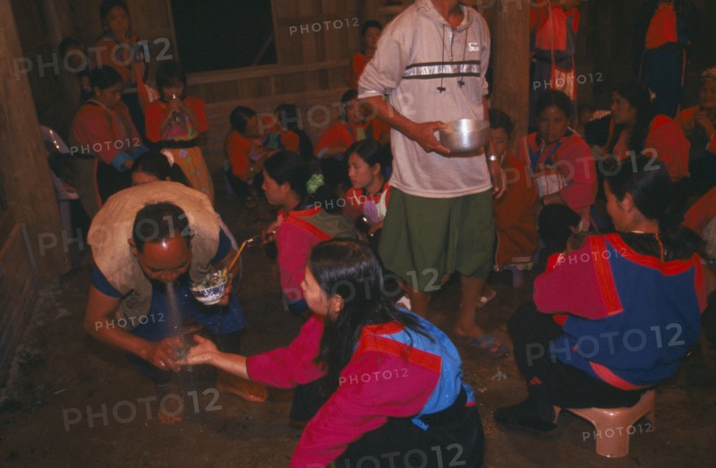 THAILAND, Chiang Rai Province, Doi Lan, Lisu shaman spraying supplicants hand at healing ceremony
