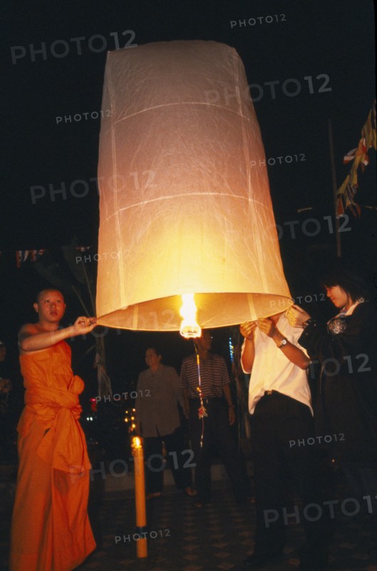 THAILAND, Chiang Mai, Wat Chaimongkon, Loi Krathong Festival aka Yi Peng. Monk and other people launching hot air balloon into the night sky