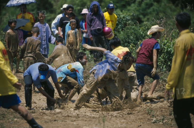 THAILAND, Yasothon, Young men frolicking in a mud pool during the Rocket Festival Bun Bang Fai