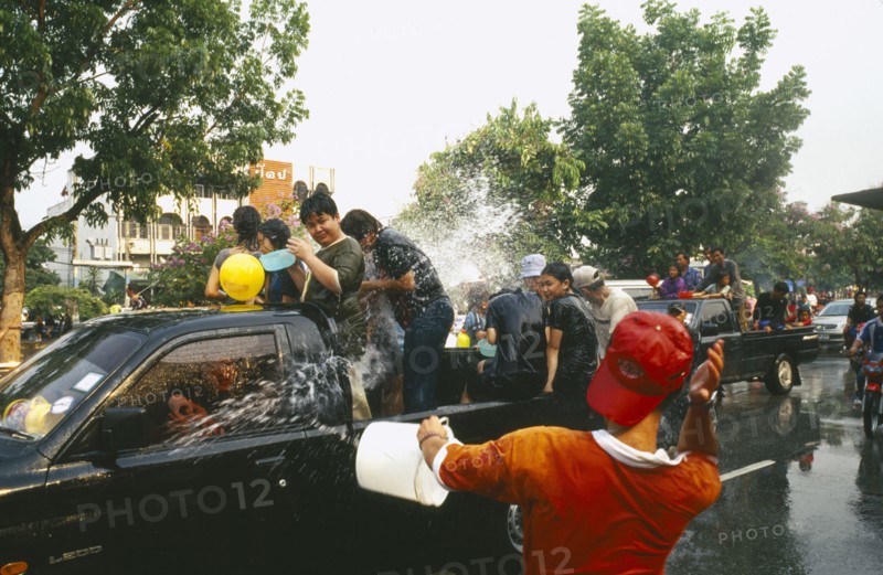 THAILAND, Chiang Mai, Songkran aka Thai New Year. Revellers in a pickup truck attempting to catch some of the water thrown at them