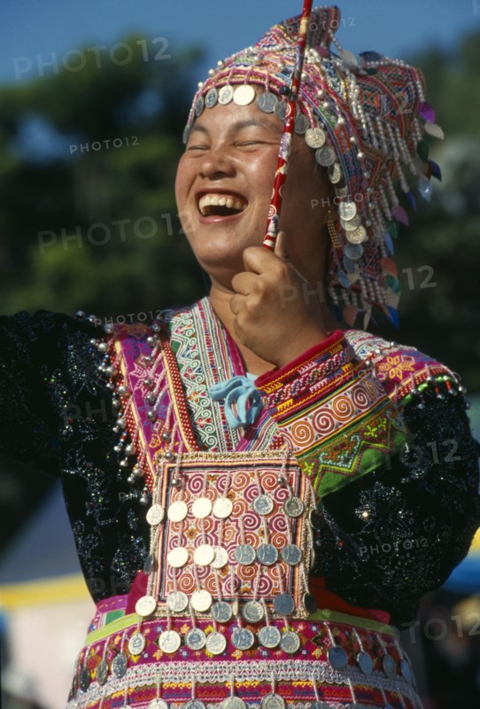 THAILAND, Chiang Mai, Hmong New Year. Young blue Hmong woman in her New Year finery laughing