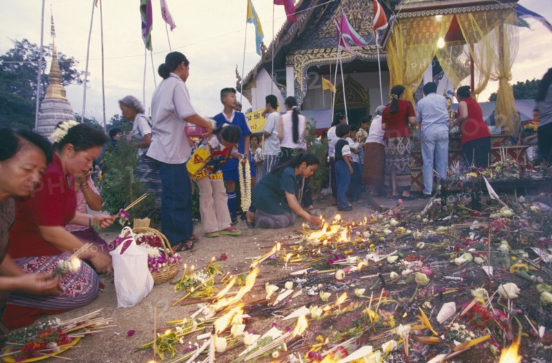THAILAND, Chiang Mai, Wat Jedi Luang, Inthakhin Ceremony. People with offerings of flowers candles and joss sticks